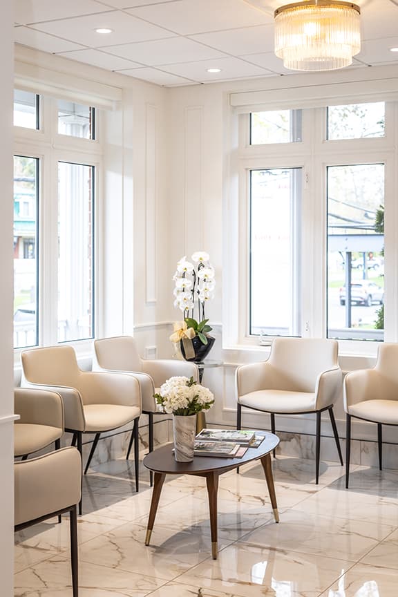 Bright boutique waiting lounge with cream armchairs, marble floors, and elegant chandelier